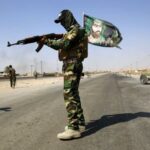 File photo of a fighter from the Shi’ite Badr Brigade militia wearing a religious flag as he guards a checkpoint outside the town of Amerli